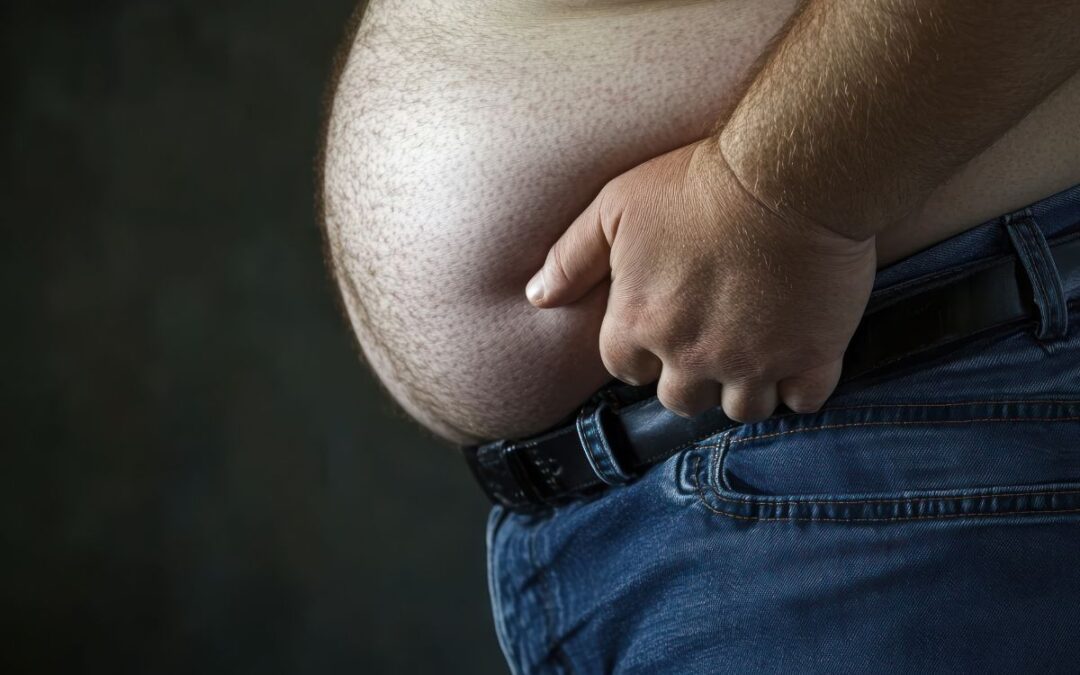 Man with a prominent belly holding his waist