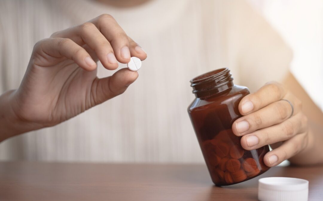 Hand taking medicine from a brown bottle