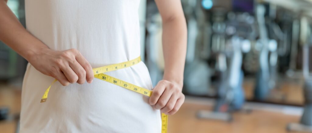 Diet and dieting. Beauty slim female body use tape measure. Woman in exercise clothes achieves weight loss goal for healthy life, crazy about thinness, nutritionist