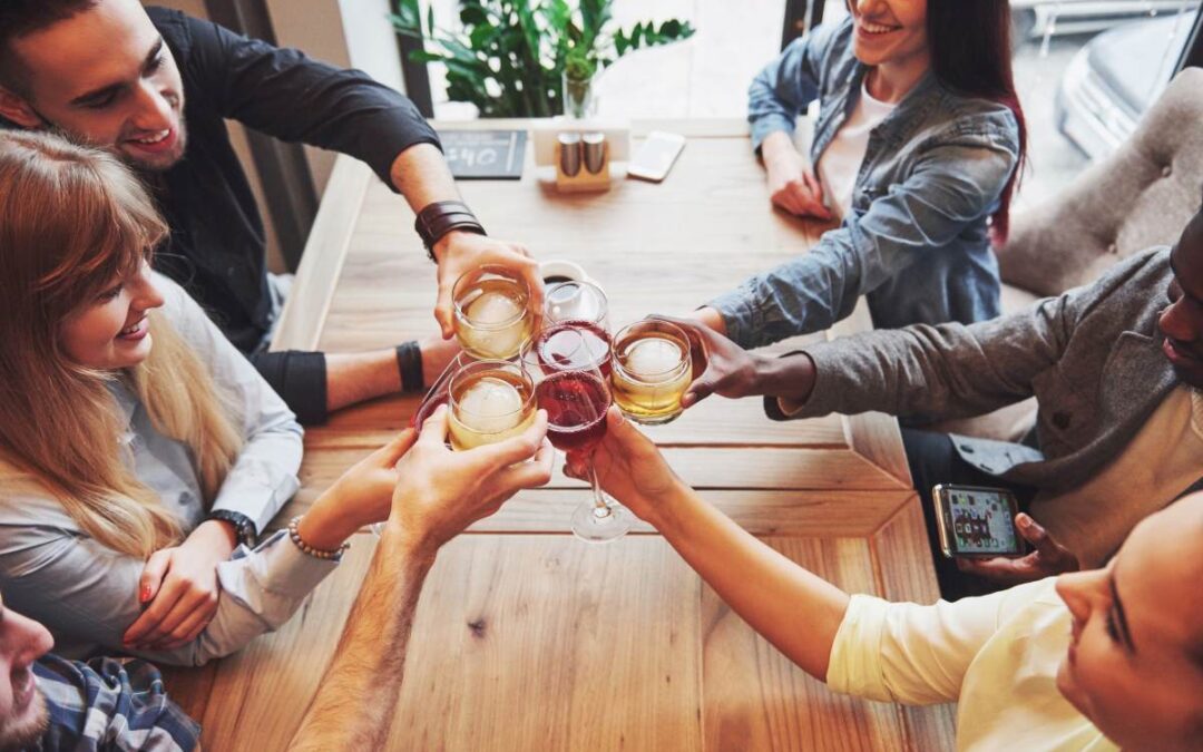 Hands of people with glasses of whiskey or wine, celebrating and toasting
